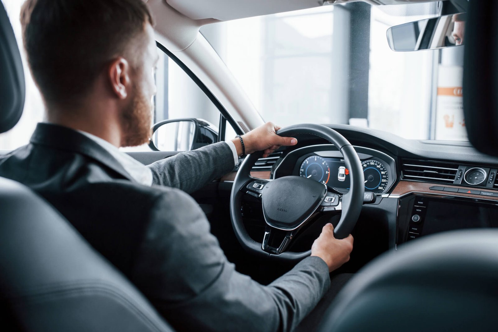 Chauffeur driving an executive car, seen from the rear passenger seat