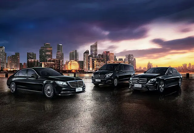 Executive chauffeur fleet lined up at night against a city skyline