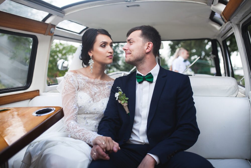 Bride and groom travelling in the back of a chauffeur-driven wedding car