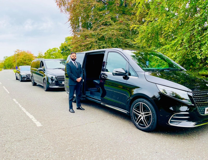 Royale Rides chauffeur beside a black Mercedes V Class before a UK airport transfer