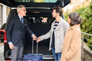 Royale Rides chauffeur greeting arriving passengers with luggage at the airport