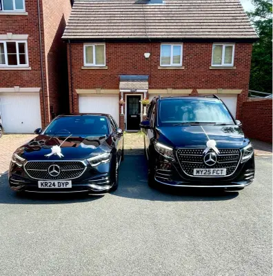Two black Mercedes wedding cars dressed with white ribbons outside a Manchester house