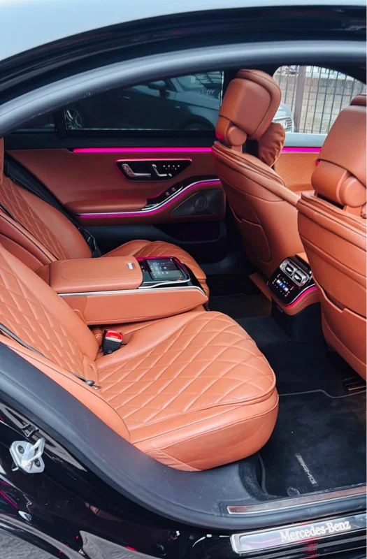 Tan quilted leather rear cabin of a Mercedes S-Class chauffeur car with ambient lighting